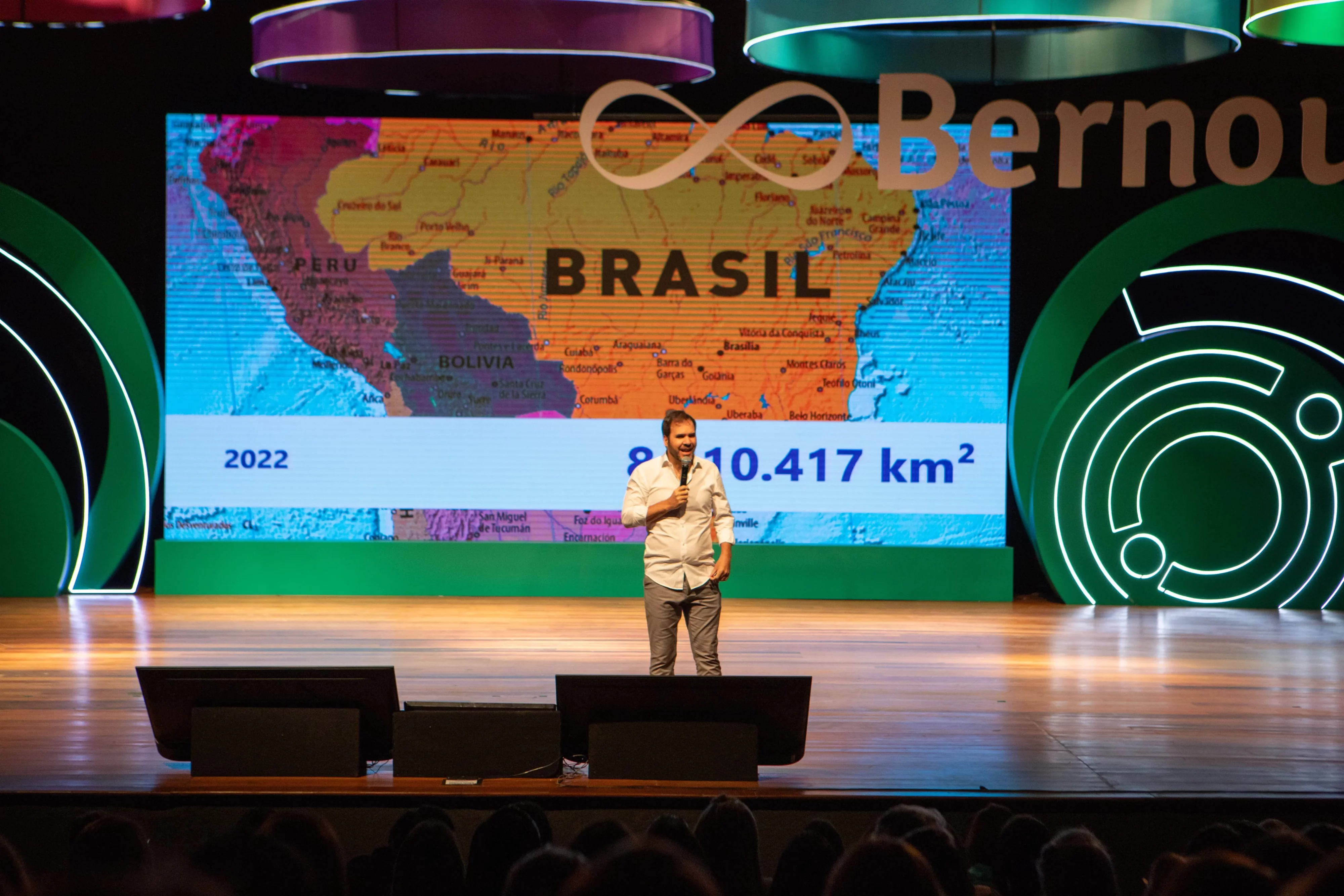 Palestrante na frente de um telão que mostra o mapa do Brasil no evento Bernoulli 360