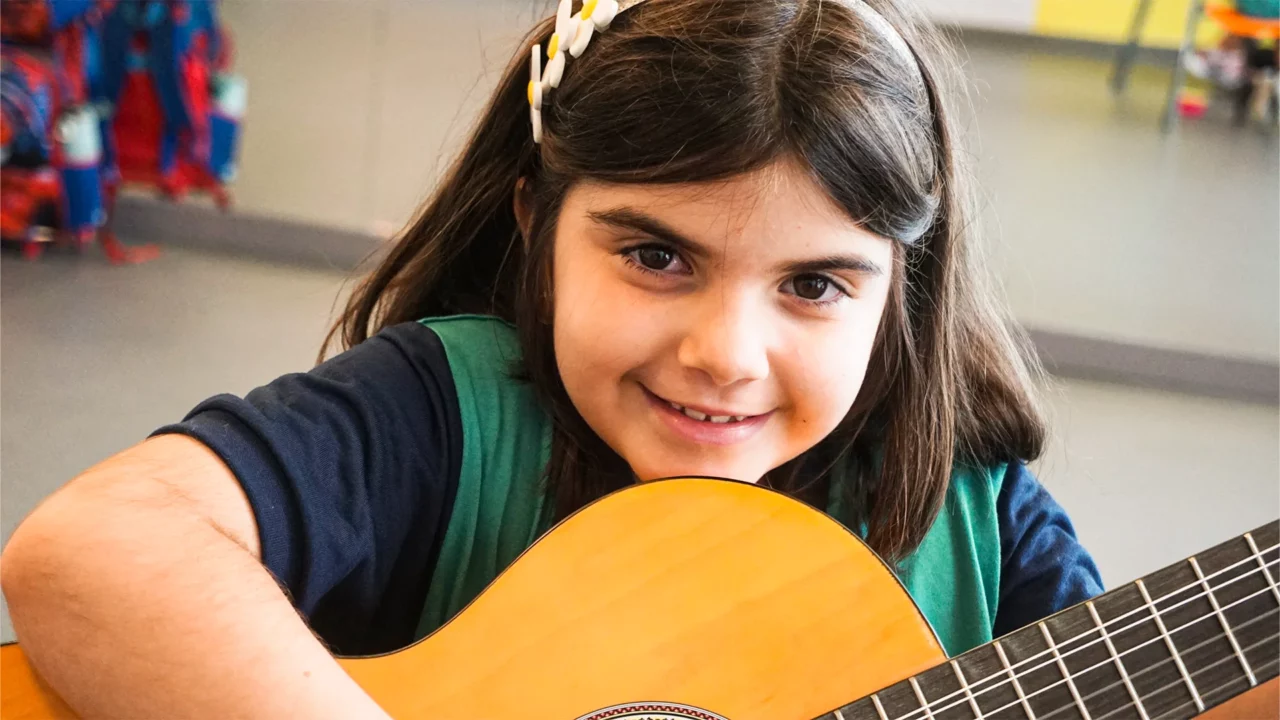 Criança posa com o violão durante aula de música no Colégio Bernoulli