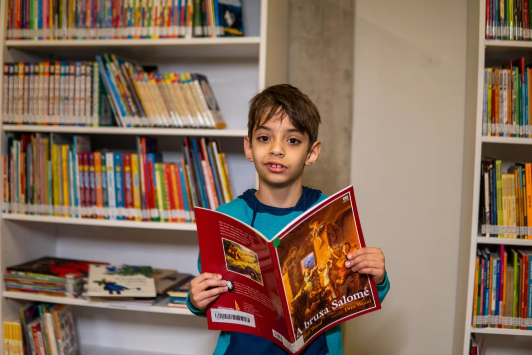 Aluno do Colégio Bernoulli realiza suas primeiras leituras na biblioteca da escola.