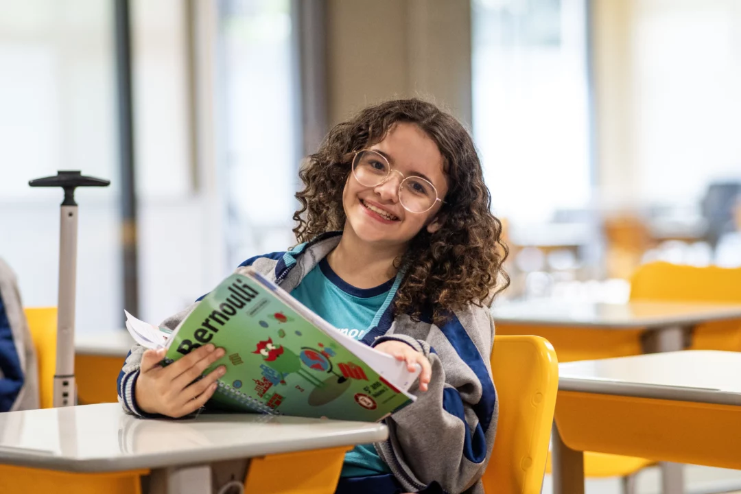 Estudante lê conteúdo da fase do Ensino Fundamental em um dos livros da coleção didática do Bernoulli Sistema de Ensino.