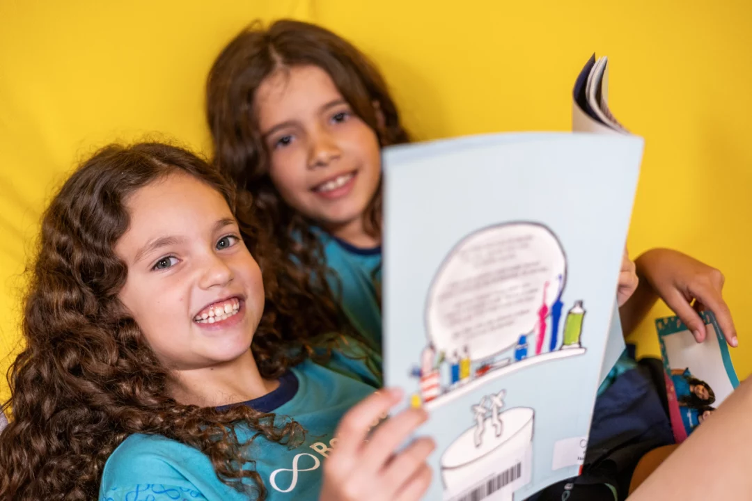 Alunos bernoulli posam lendo livros na biblioteca do colégio